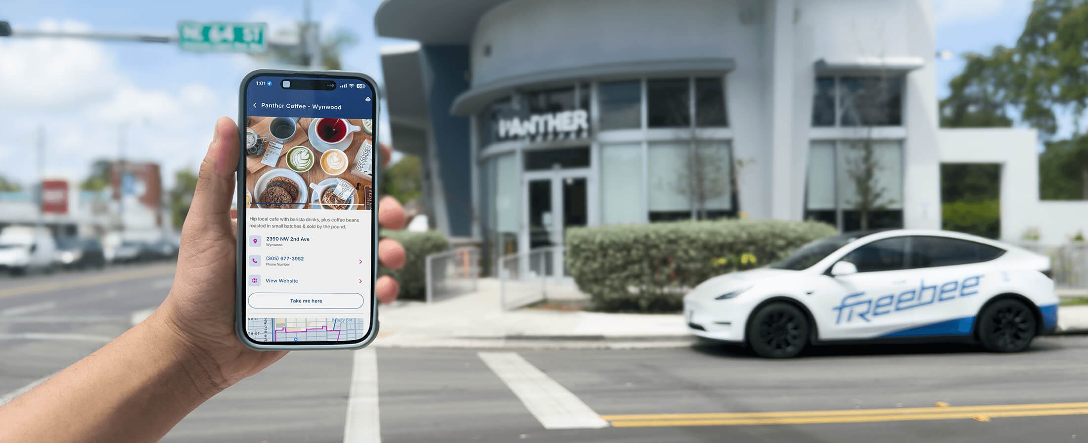 Hand holding a phone with Freebee app in front of a Freebee car